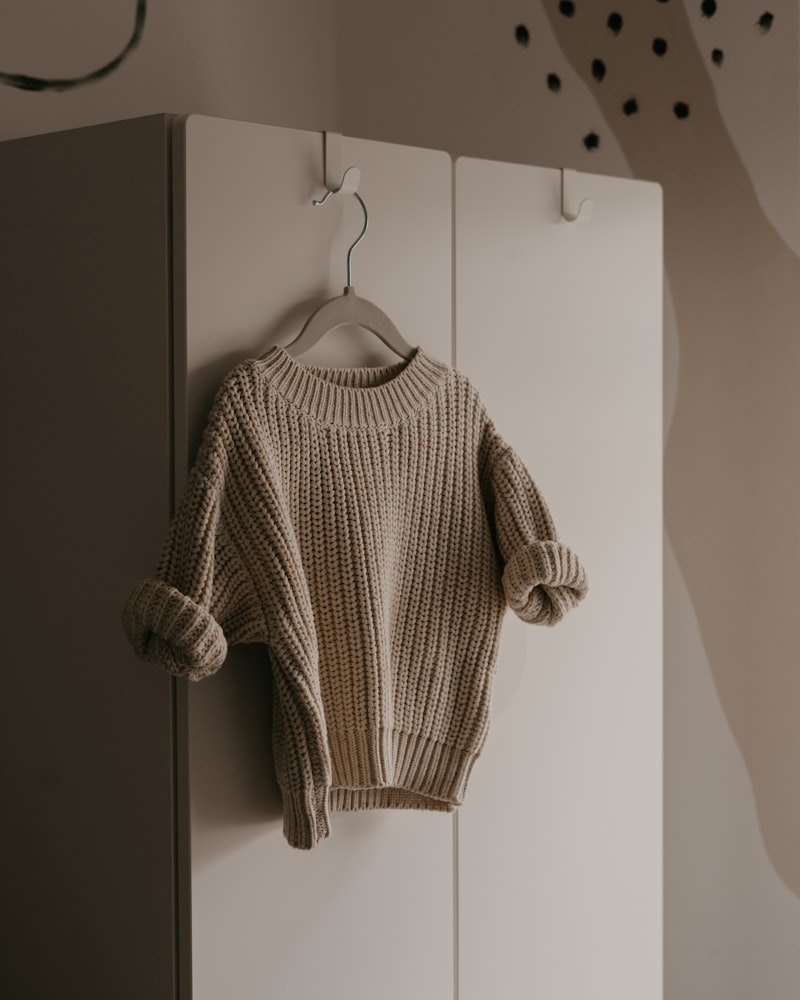 Sweater de lana crudo de punto grueso colgado en un perchero